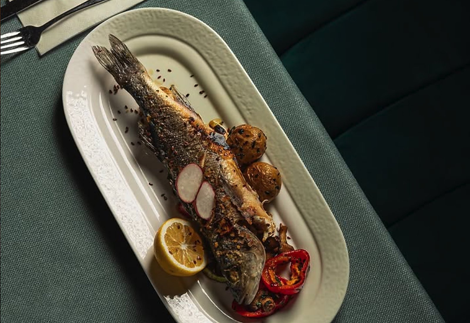 Whole sea bass baked on the bone with confit potatoes and peppers